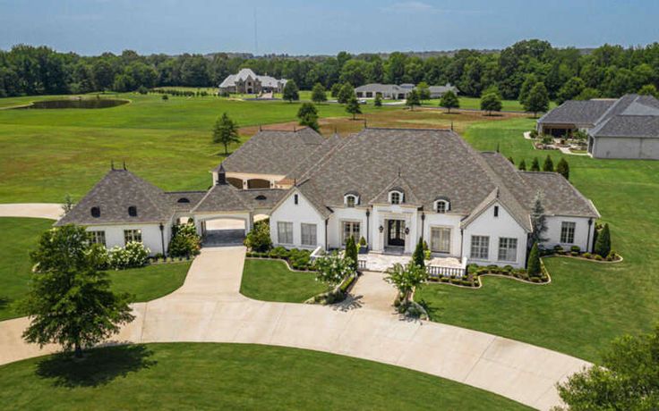 an aerial view of a large home in the middle of a green field with lots of trees