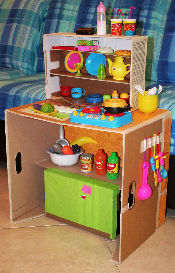 a cardboard toy kitchen set sitting on top of a floor next to a blue couch