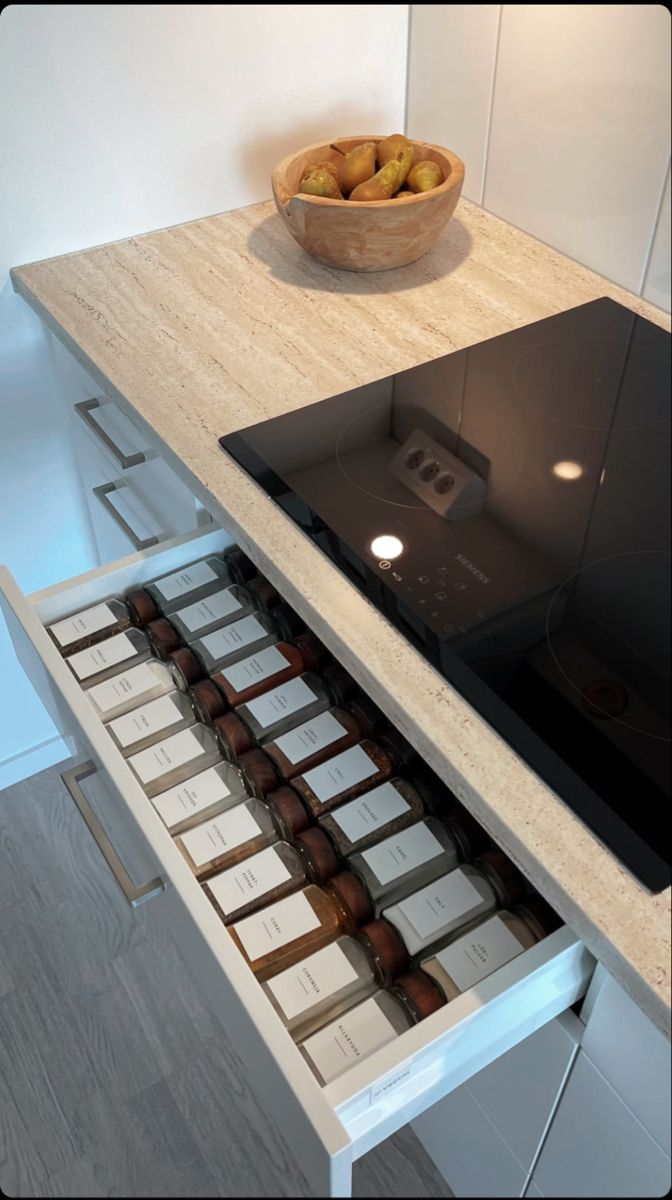 an open drawer in a kitchen with chocolates and apples on the counter next to it