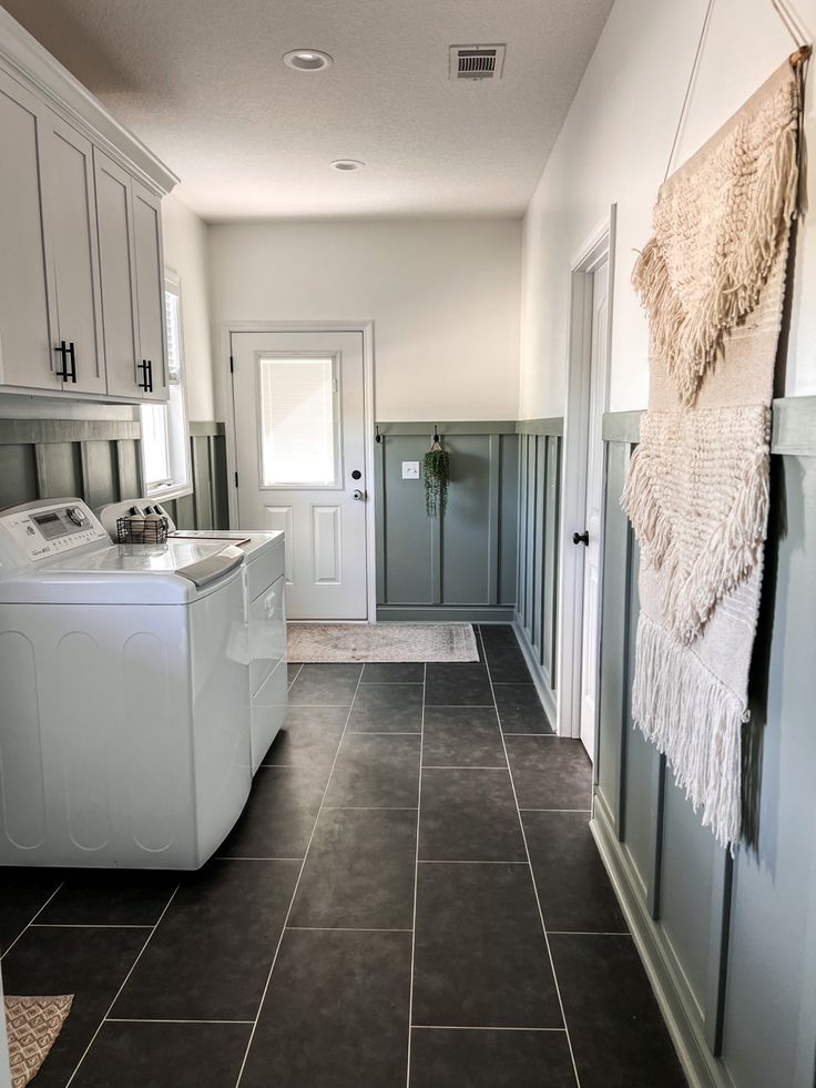 a laundry room with tile flooring and white washer and dryer in it