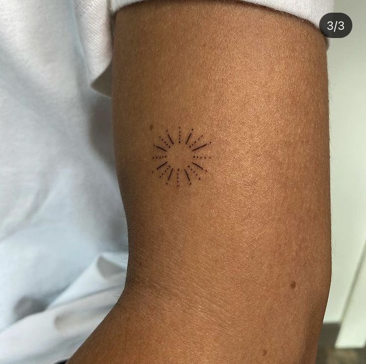 a woman's arm with a small sun tattoo on the left side of her arm