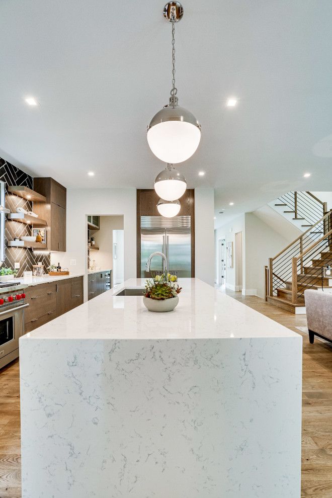 a large kitchen with an island in the middle and stairs leading up to the second floor