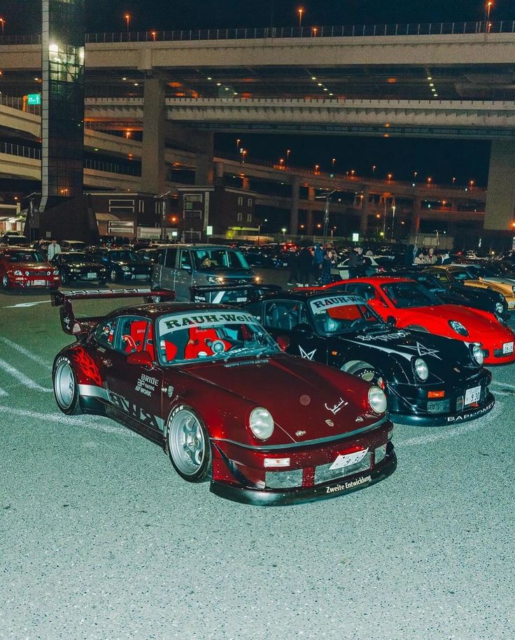 a group of cars parked in a parking lot next to an overpass at night