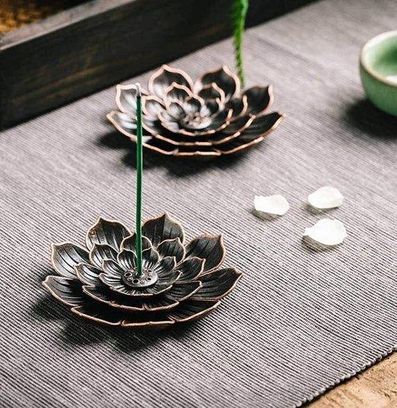 two metal flowers sitting on top of a table next to bowls and spoons with green stems sticking out of them