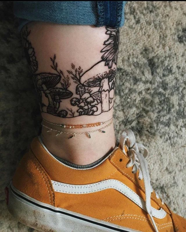 a woman's foot with a tattoo on the side of her leg and an orange shoe