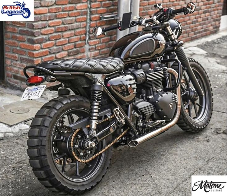 a black motorcycle parked next to a brick building