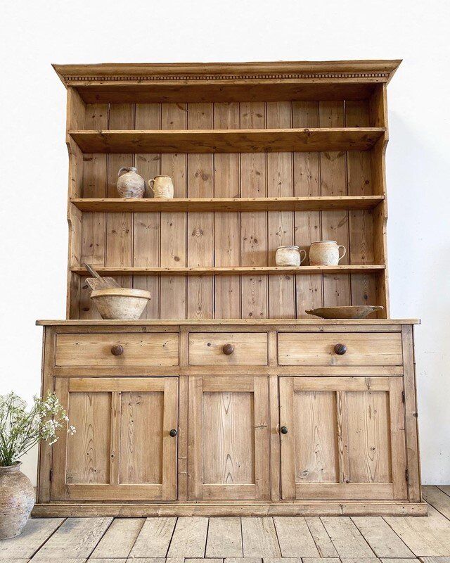 an old wooden cabinet with two bowls on top and one bowl on the bottom, in front of it