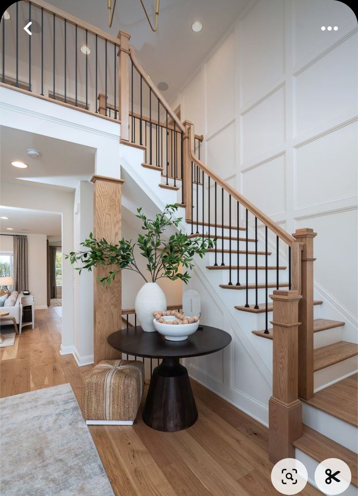 a living room filled with furniture and a stair case in front of a white wall