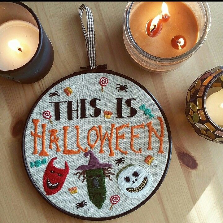 this is halloween cross - stitch pattern on a hoop with candles in the back ground