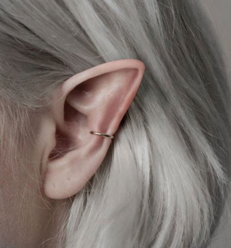 black and white photograph of a woman's left ear with a single piece of metal in the middle