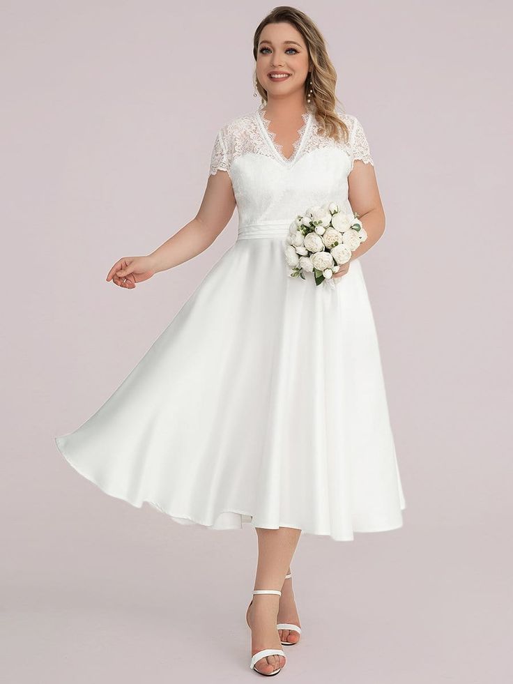 a woman wearing a white dress with lace on the neck and sleeves, holding a bouquet in her hand