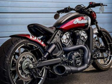 a red and black motorcycle parked in front of a blue garage door with graffiti on it