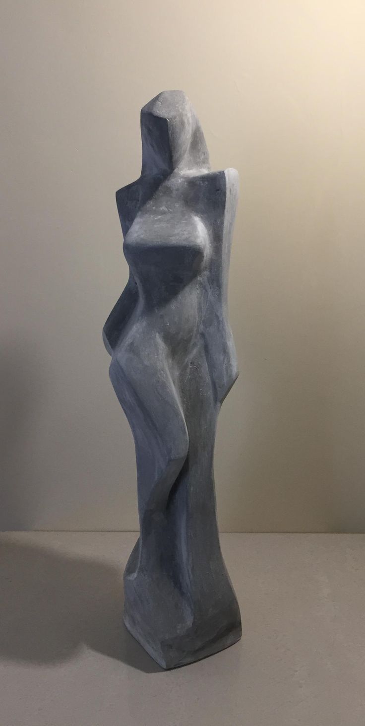 a gray sculpture sitting on top of a table next to a white wall and floor