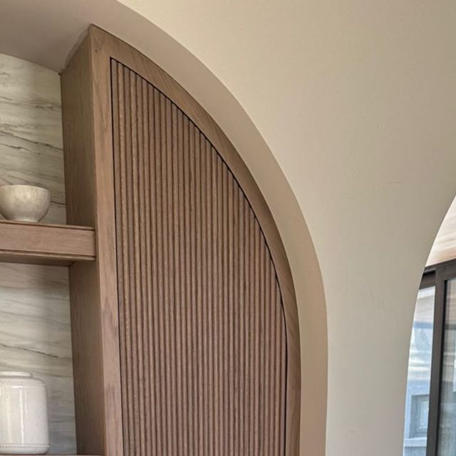 an arched wooden shelf in the corner of a room