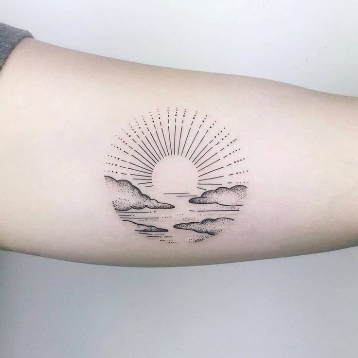 a woman's arm with a sun and clouds tattoo on the left inner arm