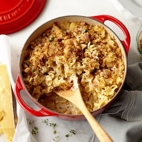 a red pot filled with macaroni and cheese on top of a white table