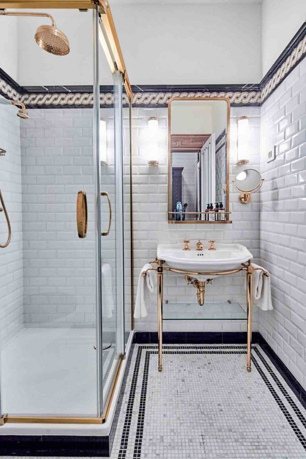 a bathroom with black and white tile flooring and gold fixtures on the shower wall