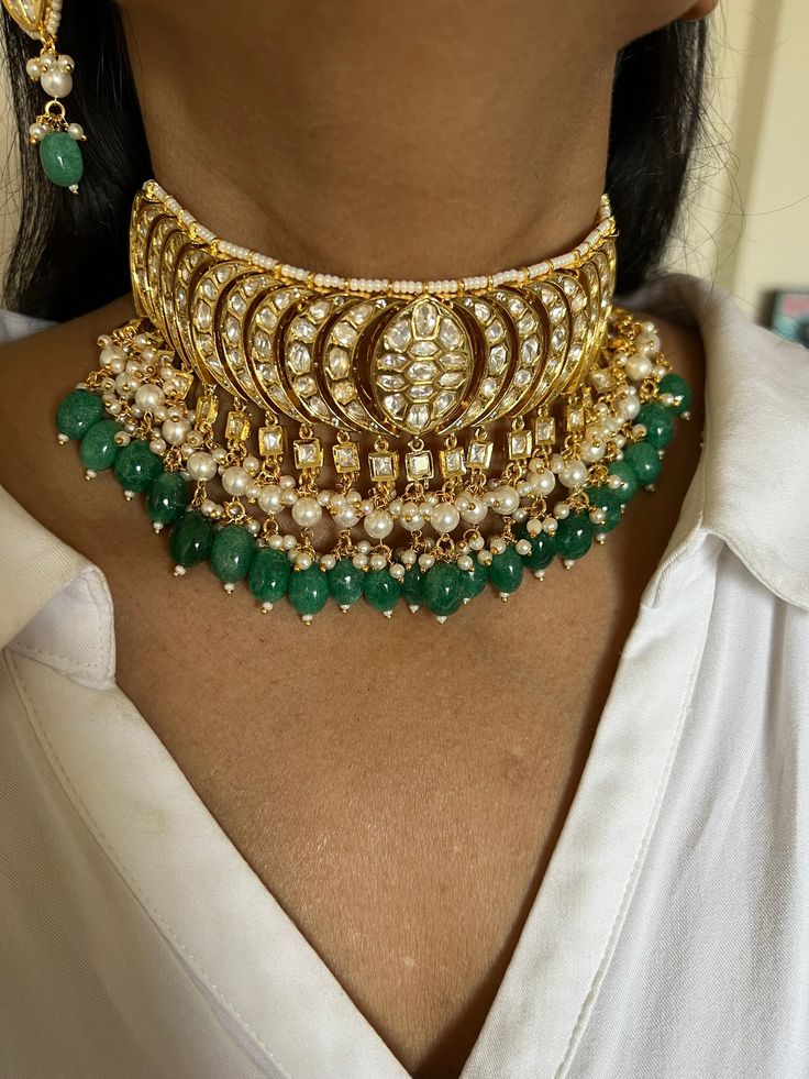 Be your own kind of beautiful. Simply a mark of royalty and elegance! You will definitely fall in love with the beautifully placed green stones with Kundan Stone embellishments. One of our favourite picks for the wedding season ❤️ The pearl drops add perfect glamour to the gorgeous piece. The pretty statement earrings add to the royalty of the stunning choker necklace. Weight of Earrings: 18 grams per pair. Length of the earrings: 6 cm Width of the earrings: 2.5 cm Green Round Kundan Necklace With Gemstone, Green Gemstone Kundan Necklace, Green Round Gemstone Kundan Necklace, Traditional Green Earrings With Jewels, Traditional Green Jeweled Earrings, Green Kundan Gemstone Jewelry Set, Kundan Jewelry Set With Green Gemstones, Hand Set Green Kundan Necklace For Anniversary, Elegant Green Kundan Necklace For Anniversary