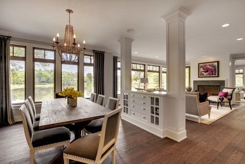 a large dining room with wooden floors and white walls, along with windows that look out onto the water