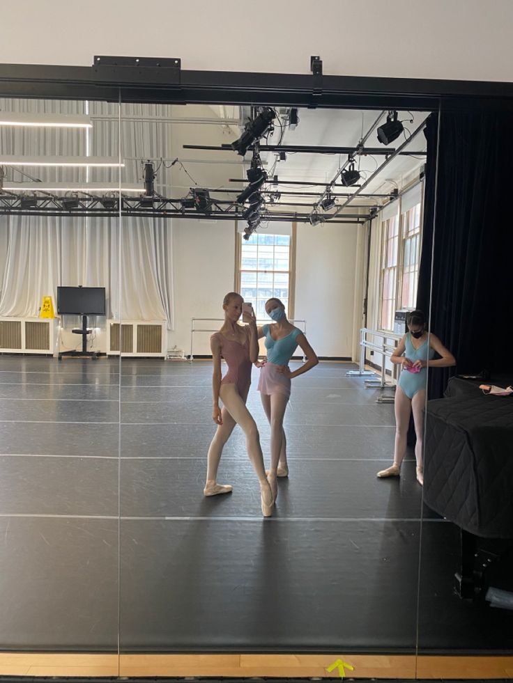 three young women in leotards and ballet clothes are standing on a dance floor