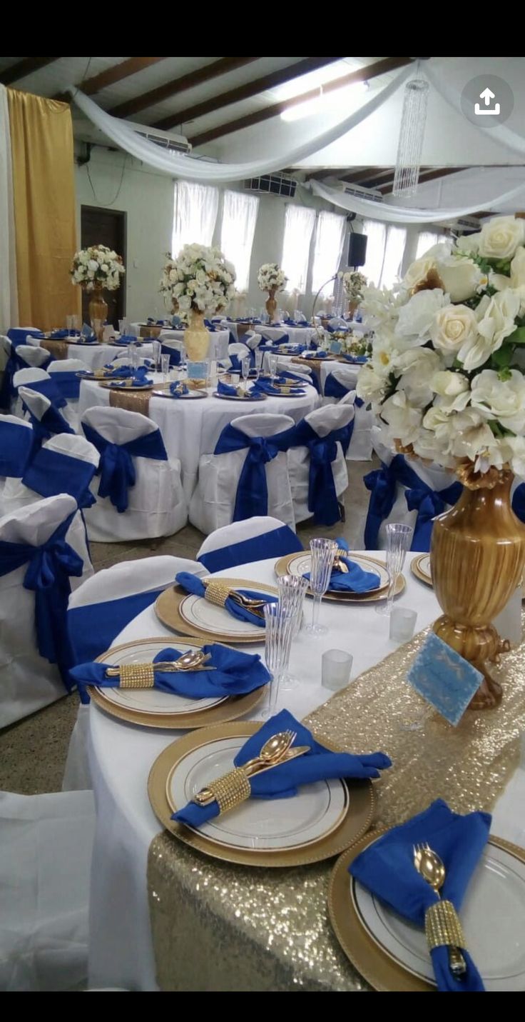 the tables are set with blue and white linens, gold chargers and silverware