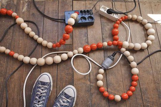 an orange and white beaded necklace with two pairs of shoes on the floor next to it