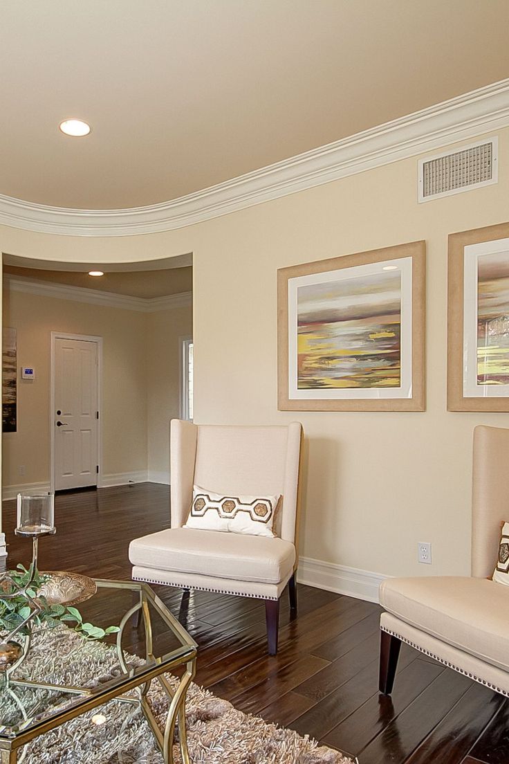 a living room with two chairs and a coffee table in front of a doorway that leads to another room