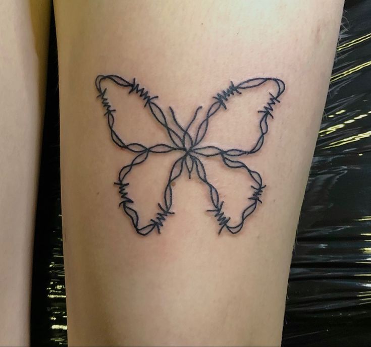 a tattoo on the leg of a woman with barbed wire in the shape of a butterfly