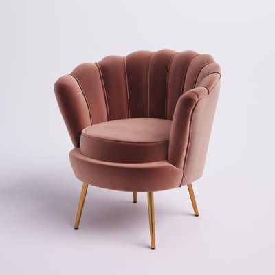 a pink velvet chair with gold legs and a round footstool in front of a white background