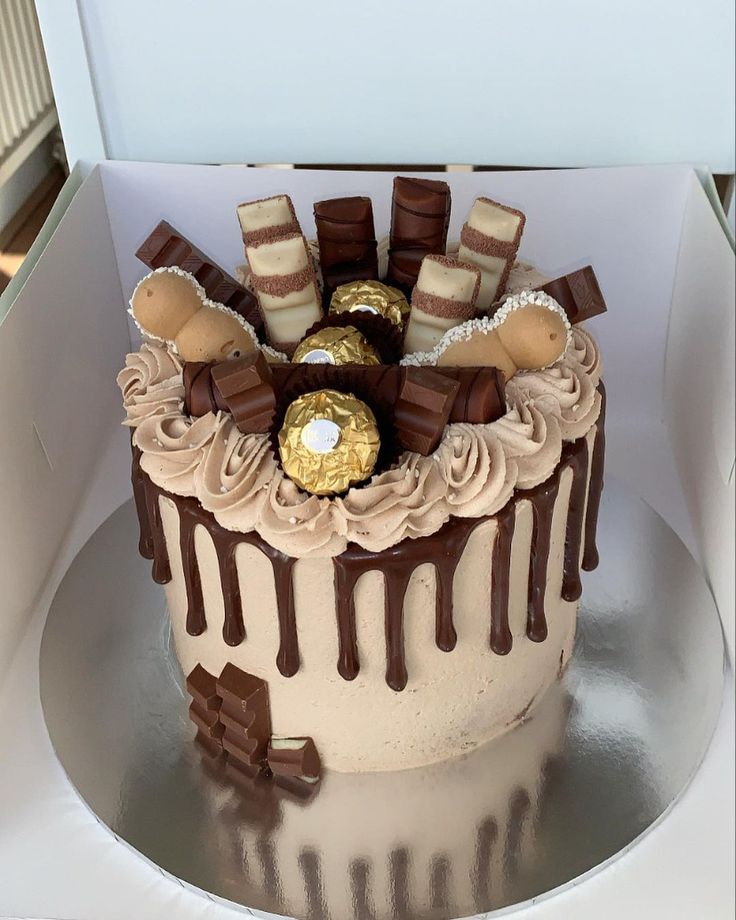 there is a cake with chocolates and candy on the top it sits in a box