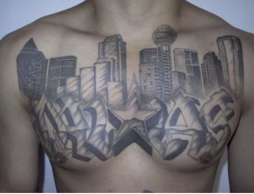 a man's chest with tattoos on it and buildings in the backgrund