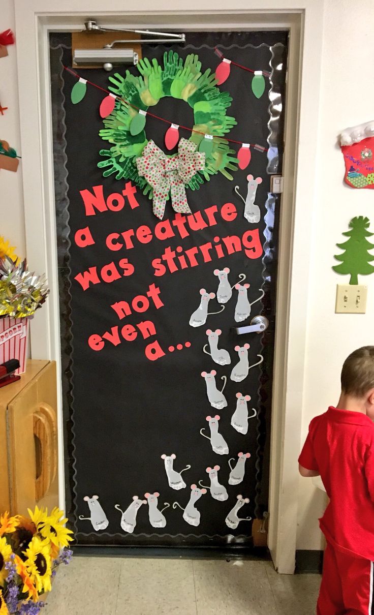 a young boy standing in front of a door decorated with christmas decorations