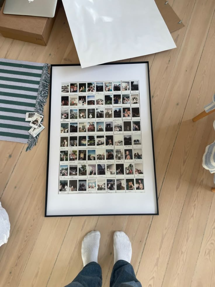 a person standing in front of a framed photo on the floor with their feet propped up