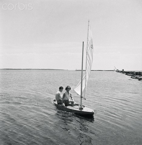 two people on a small sailboat in the water