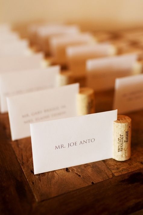 there is a row of wine corks on the table with place cards in front of them