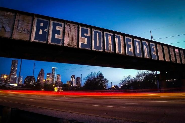 an old train bridge with the word be somewhere written on it over a city street