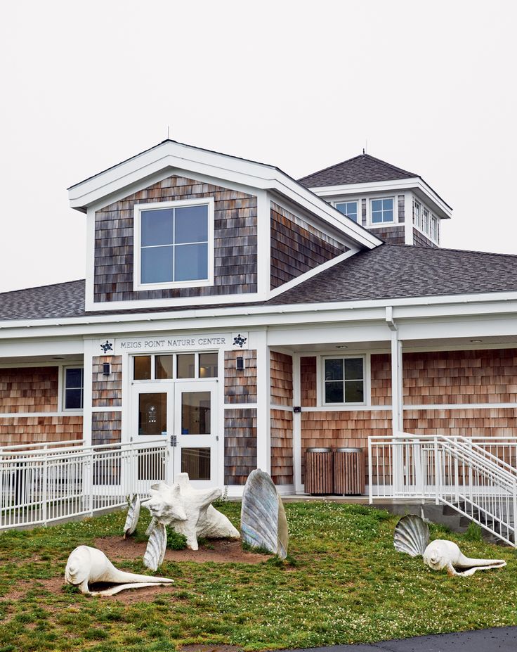 the front of a house with lawn and sculptures on the grass in front of it