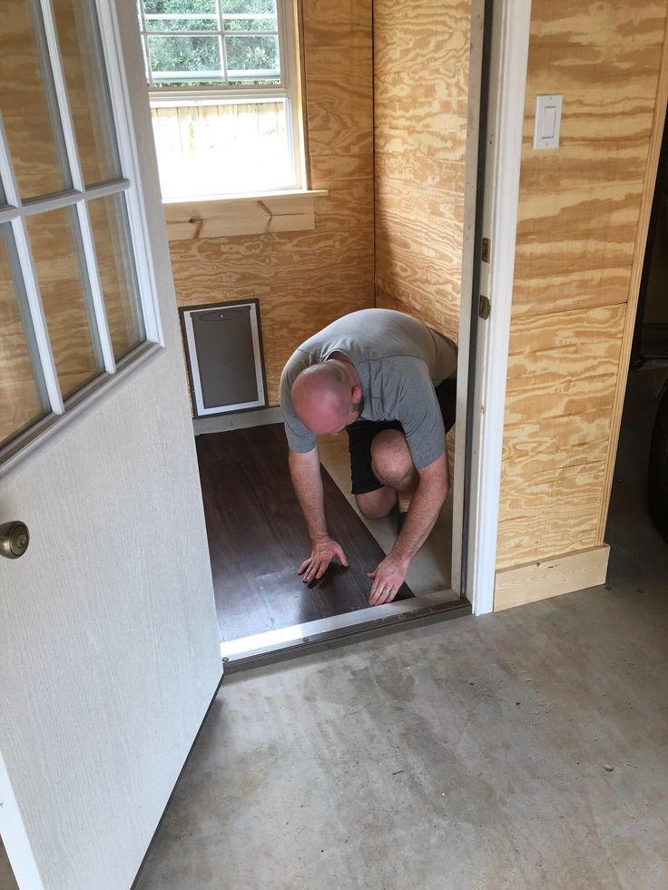 a man kneeling down on the floor in front of a door with an open window