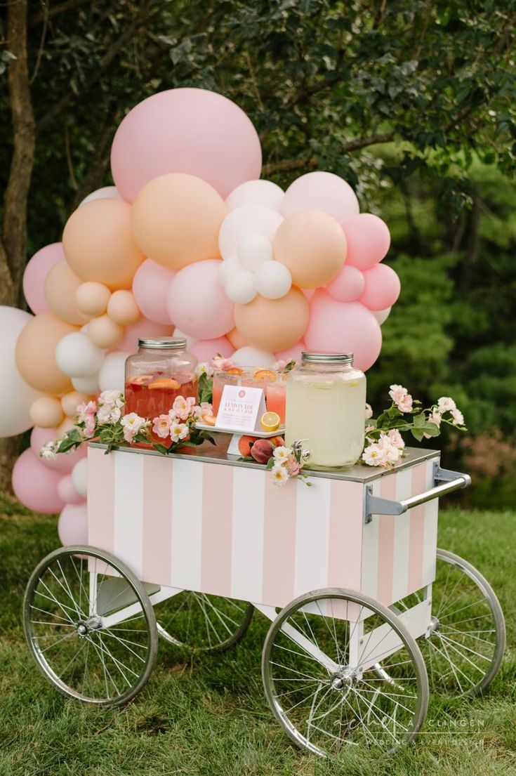 a pink and white cart with balloons on it