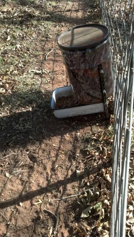 a trash can sitting next to a wire fence