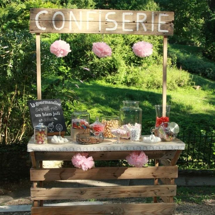 a wooden table topped with lots of desserts and candy covered in pink tissue pom poms