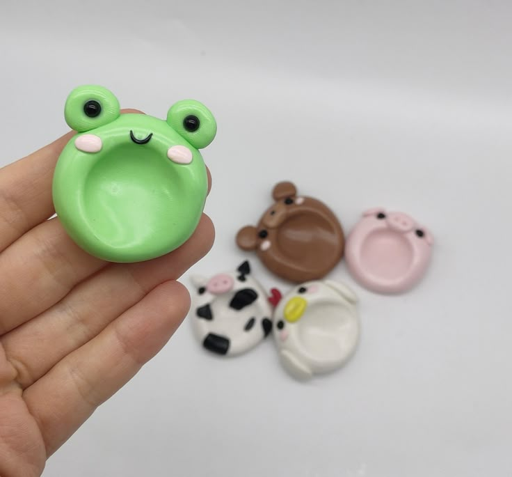 a hand holding three small plastic animal magnets