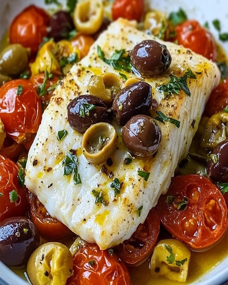 fish with olives and tomatoes in a white bowl