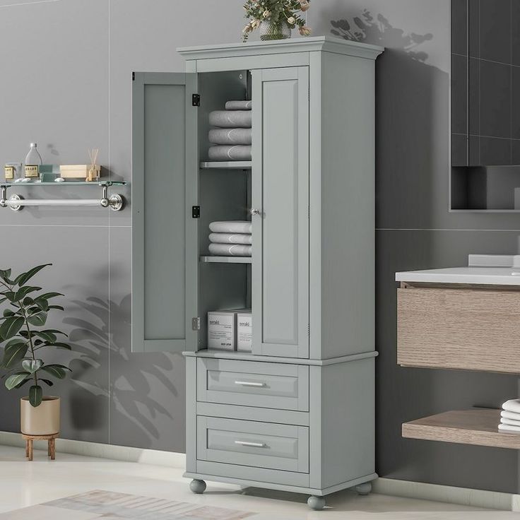 a bathroom with a gray cabinet next to a plant and toilet paper dispenser