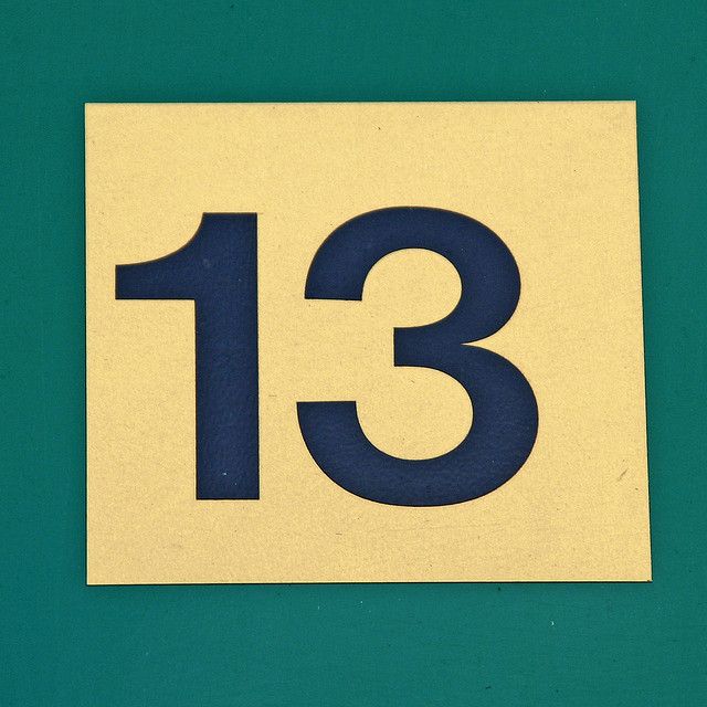 a close up of a number 13 on a green surface with white and blue lettering