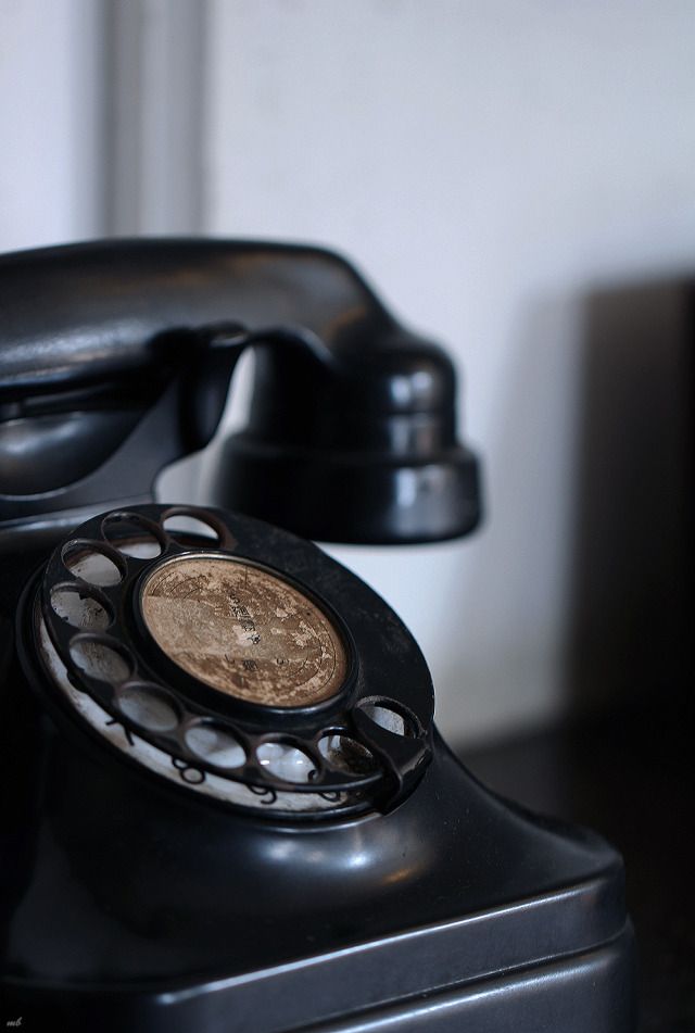 an old fashioned black telephone sitting on top of a table