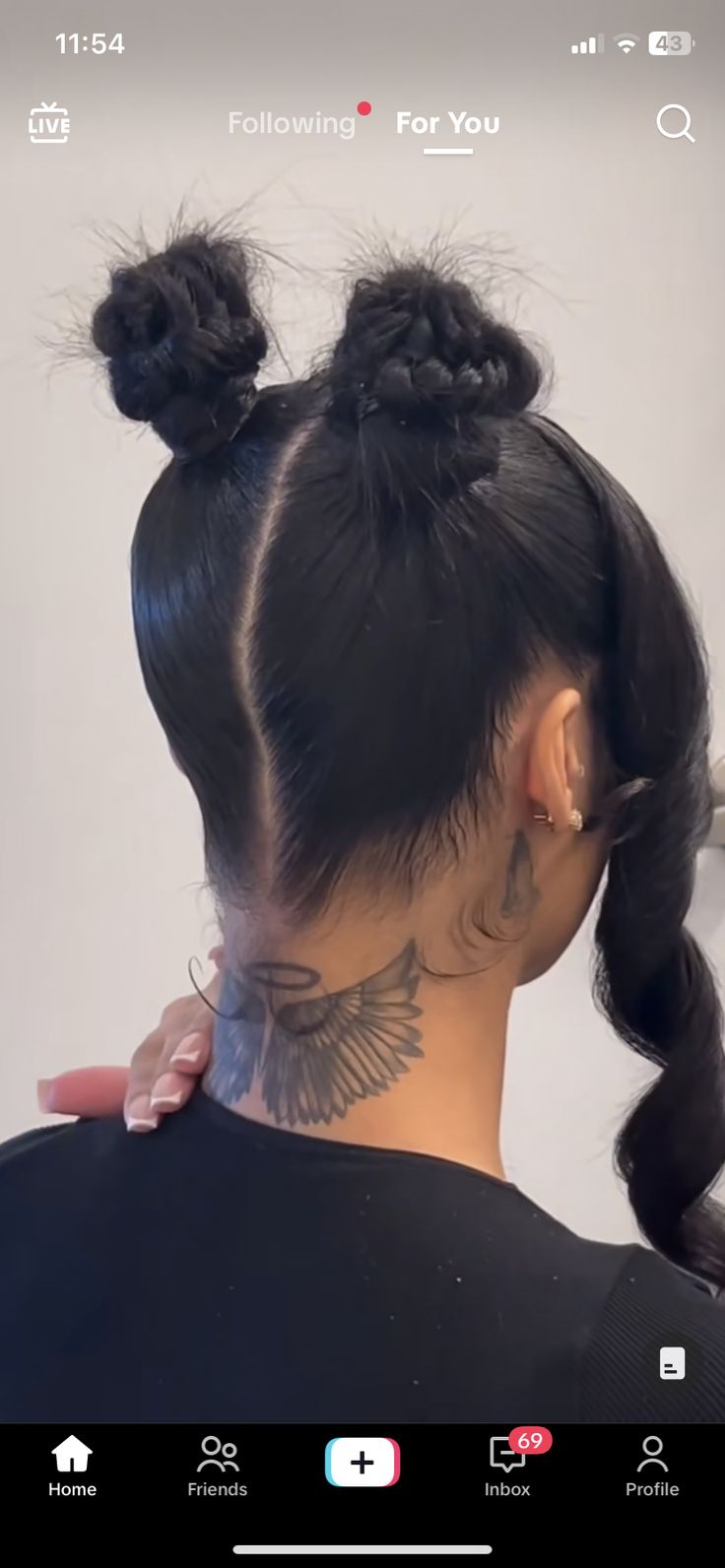 the back of a woman's head with two buns and tattoos on her neck