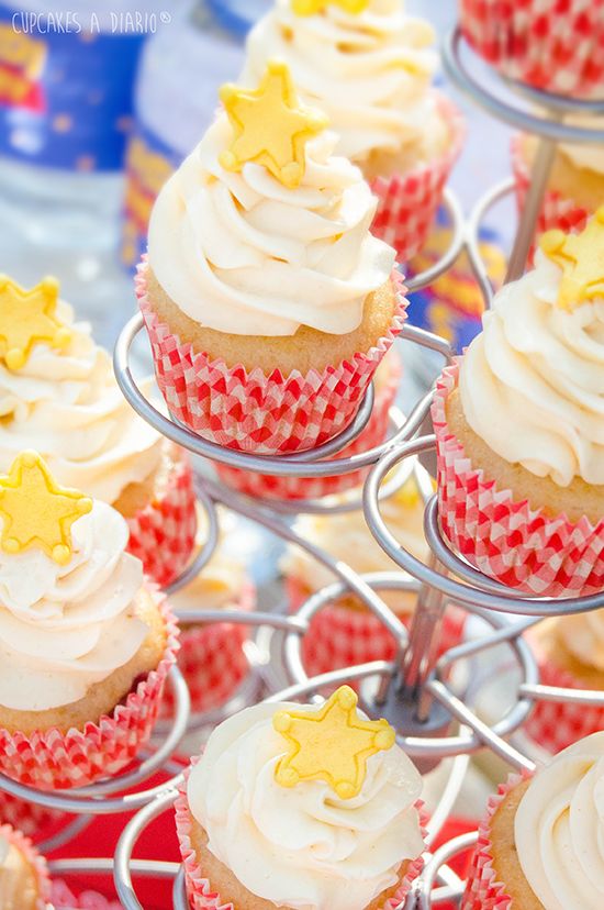 cupcakes with white frosting and yellow stars on top are sitting on a wire rack