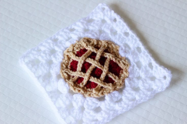 a small crocheted pie sitting on top of a white doily in the shape of a square