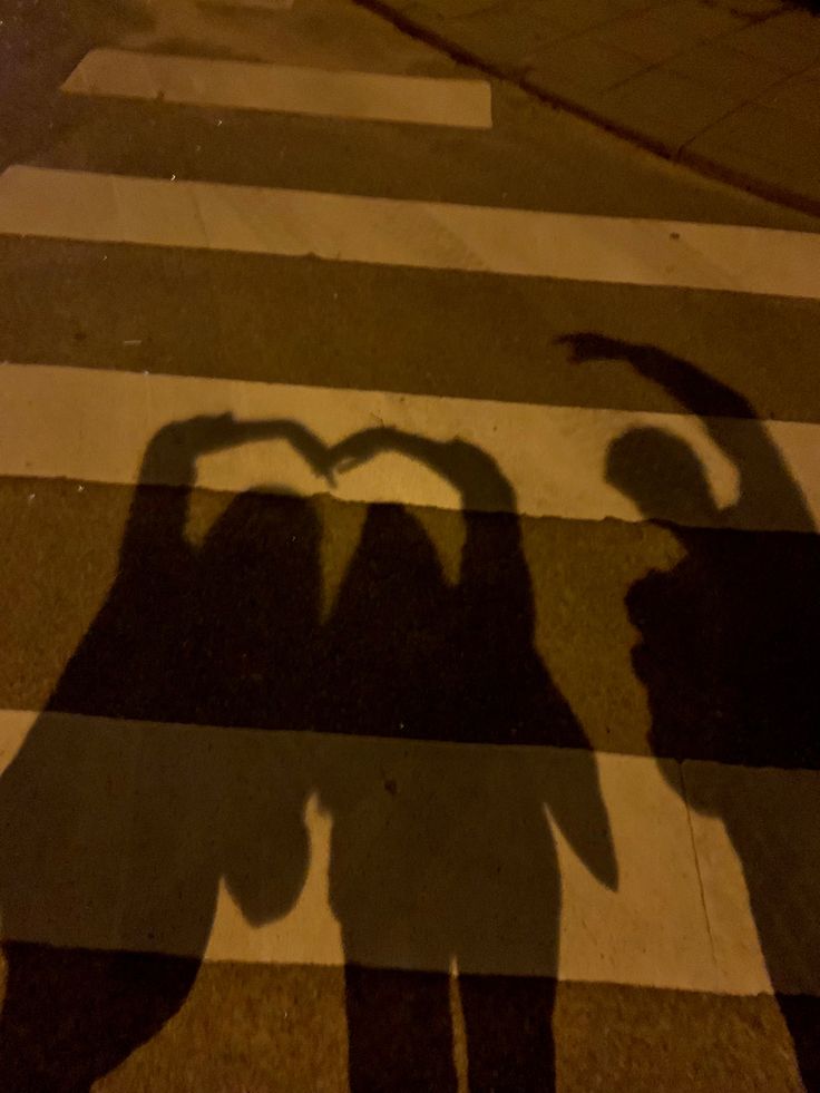 the shadow of two people standing in front of a crosswalk